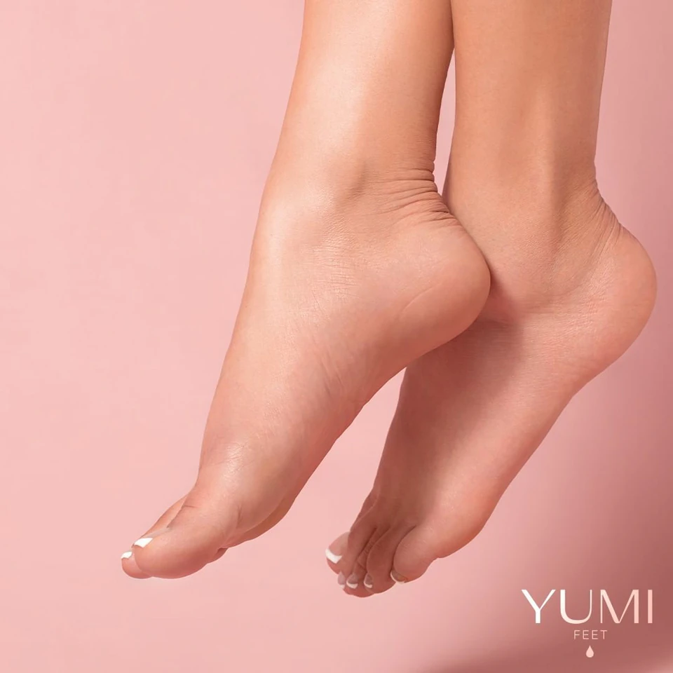 Piedi e talloni curati nella fotografia YUMI Feet su fondo rosa